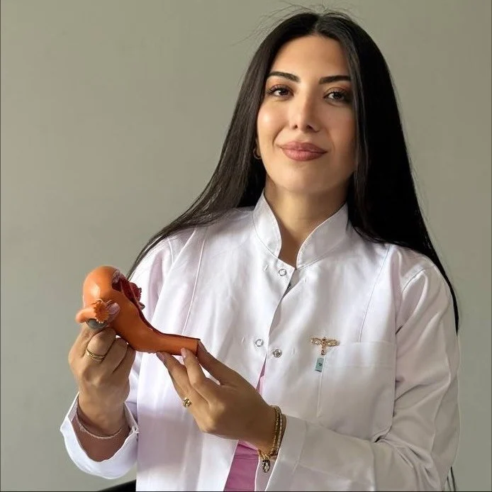 Dr. Ceyran İmaməliyeva ağ xalatda, əlində uşaqlıq maketi